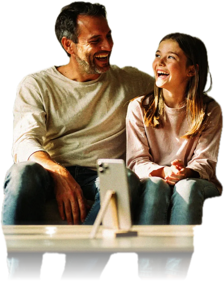 Un padre y su hija sentados juntos en el sofá, escuchando una grabación en el teléfono de él