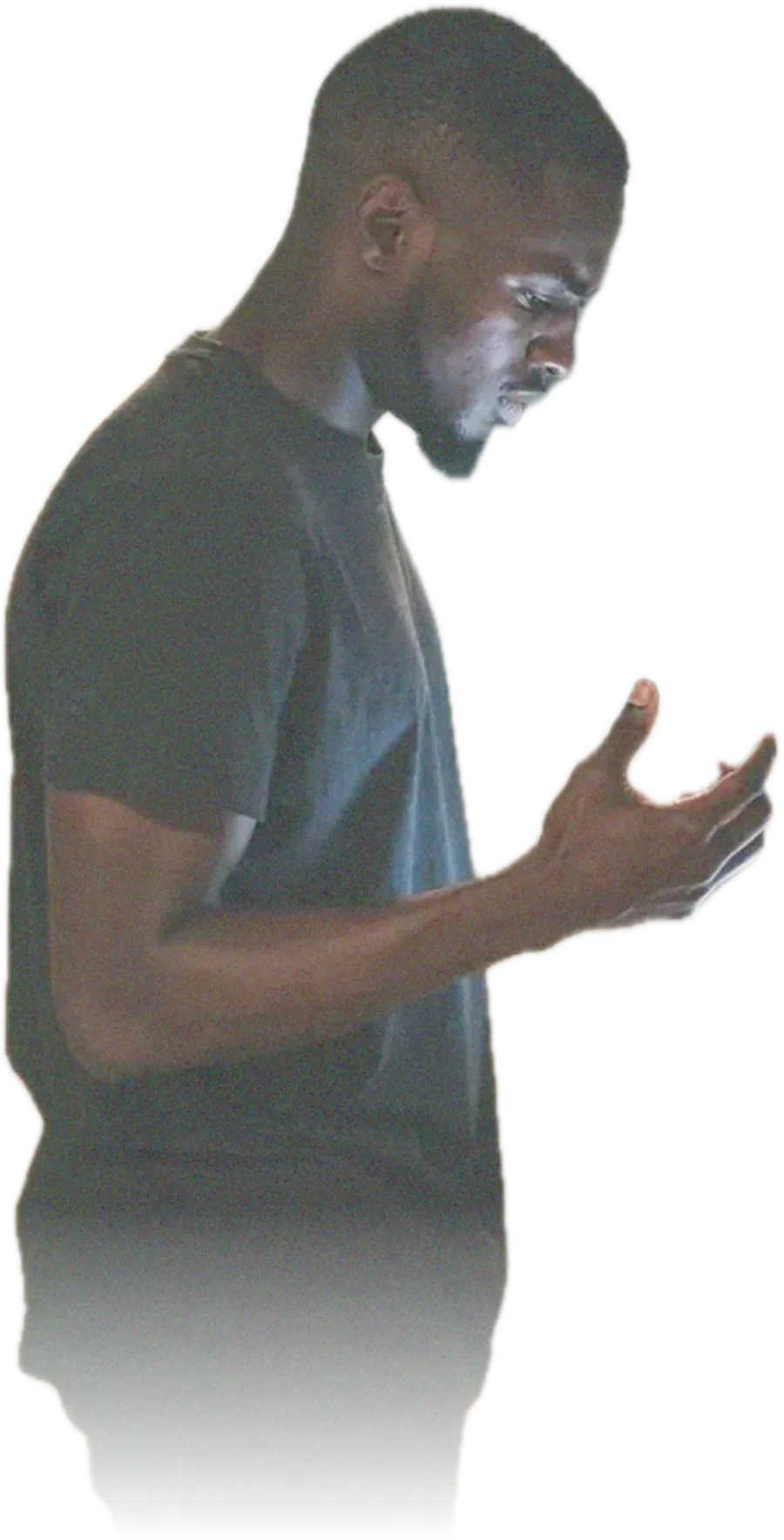 A young man standing in a hallway looking down at a ringing phone on a side table without picking it up