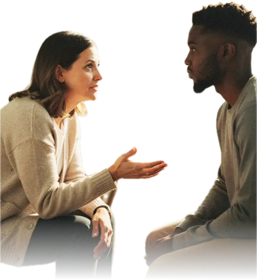 A speech and language therapist mid-explanation with a patient listening, seated facing each other in a plain therapy room